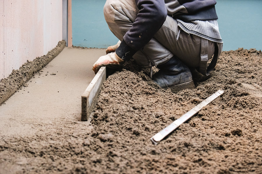 construction worker kneeling flattening the cement floor